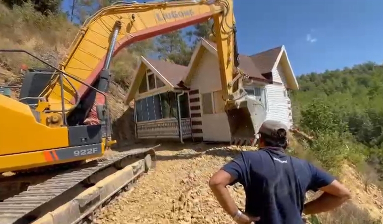 Yıkım kararı verilen konteyner evini iş makinesiyle karadan rayla yürütüp taşıdı