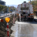 Muhtar, toz çıkmasın diye caddeyi suluyor