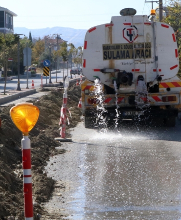 Muhtar, toz çıkmasın diye caddeyi suluyor