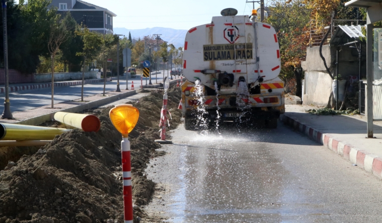 Muhtar, toz çıkmasın diye caddeyi suluyor